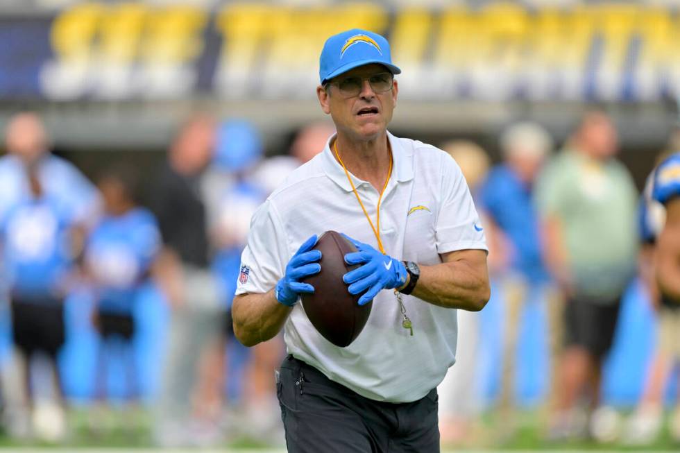 Los Angeles Chargers head coach Jim Harbaugh prepares to throw a pass before a preseason NFL fo ...