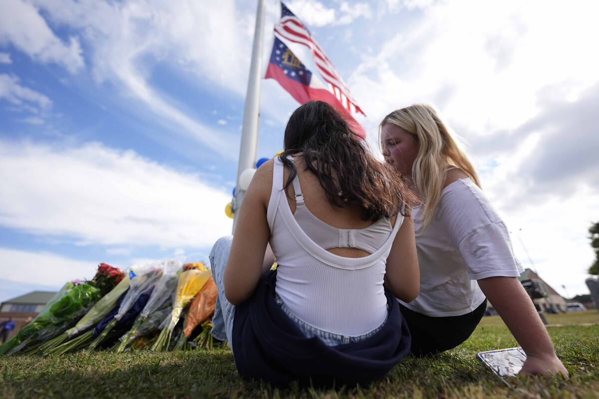 Two students view a memorial as the flags fly half-staff after a shooting Wednesday at Apalache ...