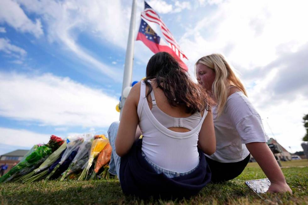 Two students view a memorial as the flags fly half-staff after a shooting Wednesday at Apalache ...