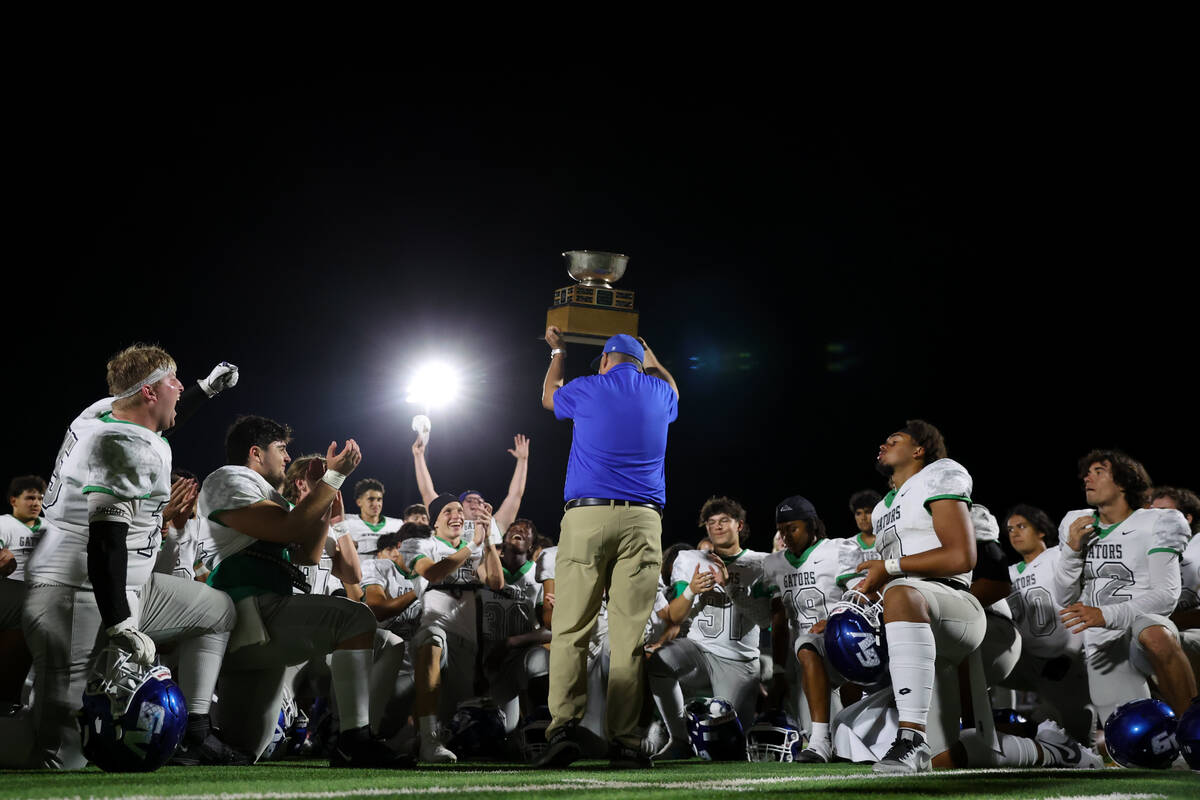 Green Valley head coach Bill Powell holds the Henderson Bowl trophy up after his team won a hig ...