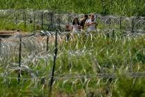 FILE - Migrants walk along concertina wire toward Border Patrol officers after illegally crossi ...