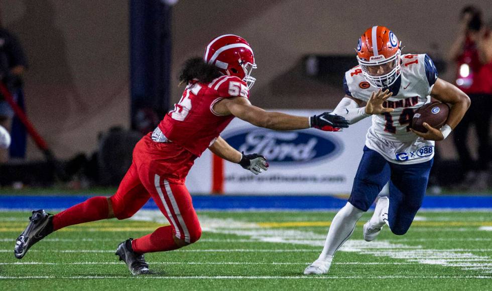 Bishop Gorman quarterback Maika Eugenio (14) looks to evade a tackle attempt by Mater Dei lineb ...