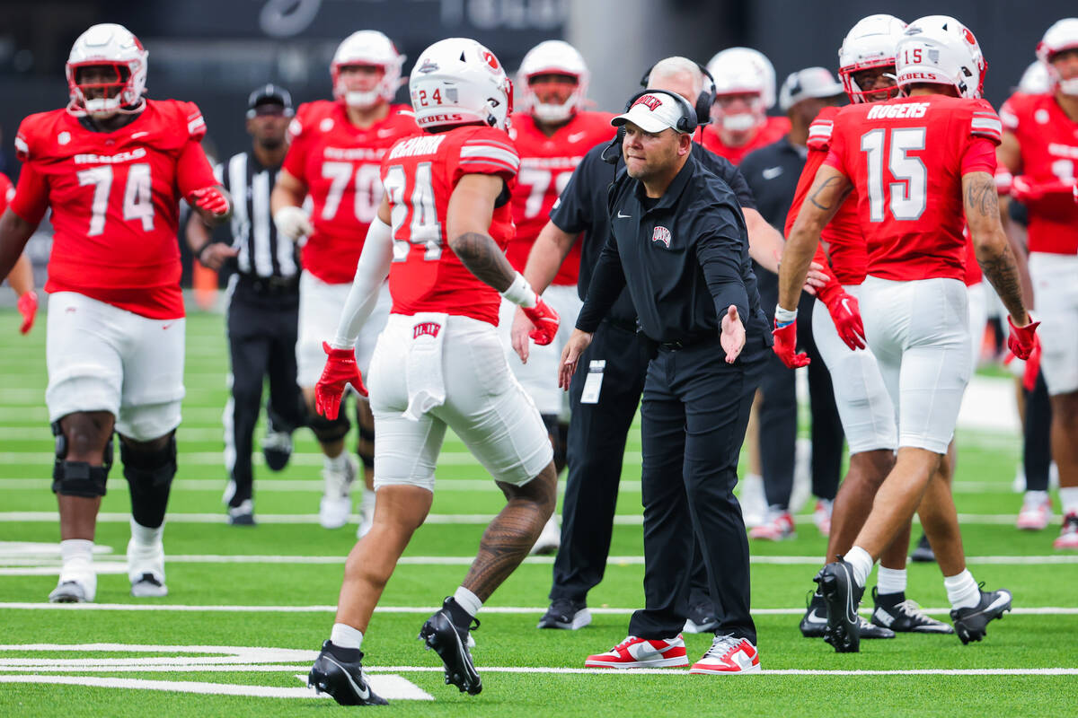 UNLV head coach Barry Odom high-fives players as they run to the sidelines during an NCAA footb ...