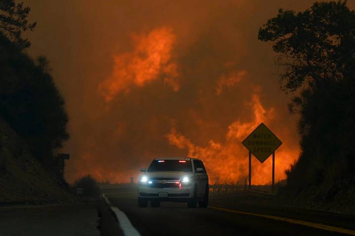 The Line Fire jumps highway 330 as an emergency vehicle is driven past Saturday, Sept. 7, 2024, ...