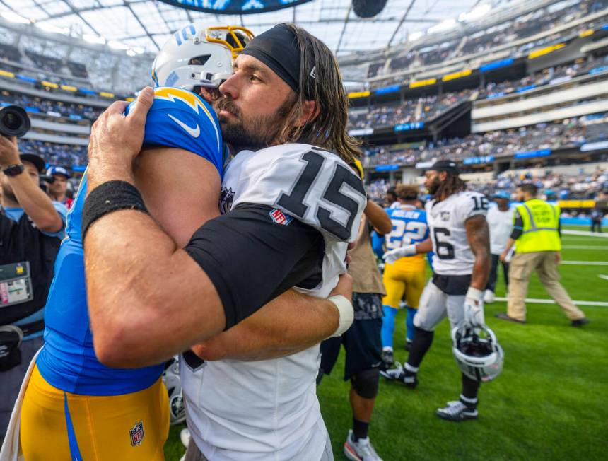 Raiders quarterback Gardner Minshew (15) gets a hug from Los Angeles Chargers quarterback Justi ...