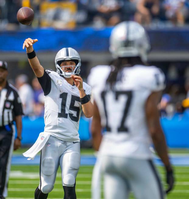 Raiders quarterback Gardner Minshew (15) tosses the ball to wide receiver Davante Adams (17) du ...