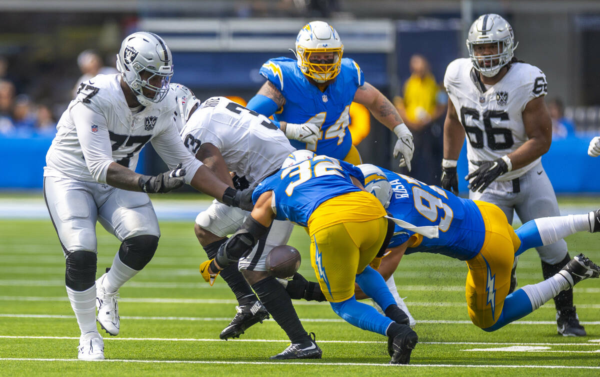 Raiders running back Zamir White (3) has the ball poked away by Los Angeles Chargers linebacke ...