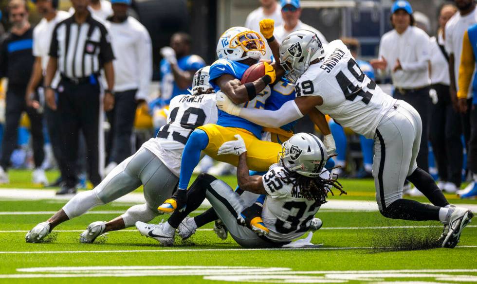 Los Angeles Chargers wide receiver Derius Davis (12) is gang tackled by Raiders defensive end C ...