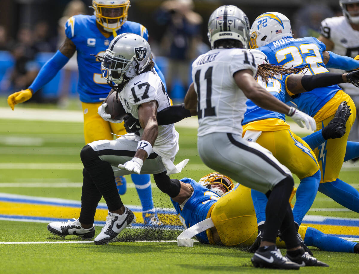 Raiders wide receiver Davante Adams (17) works to break a tackle attempt by Los Angeles Charger ...