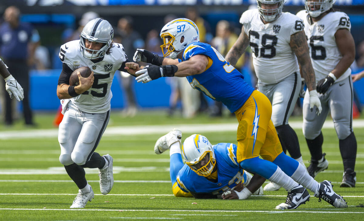 Raiders quarterback Gardner Minshew (15) looks to avoid a tackle on a run by Los Angeles Charge ...