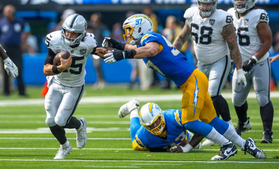 Raiders quarterback Gardner Minshew (15) looks to avoid a tackle on a run by Los Angeles Charge ...