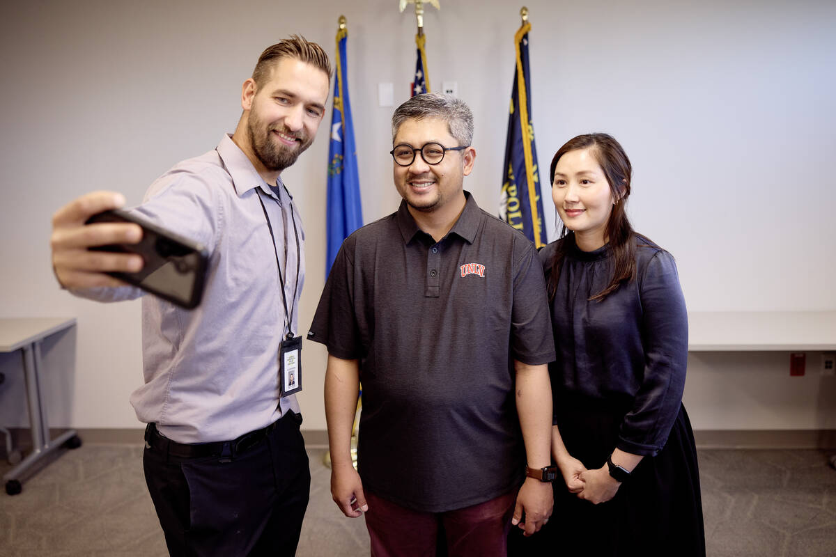 Metro officer Jacob Noriega, left, takes a selfie with UNLV professor Daraboth “Bot” Rith a ...