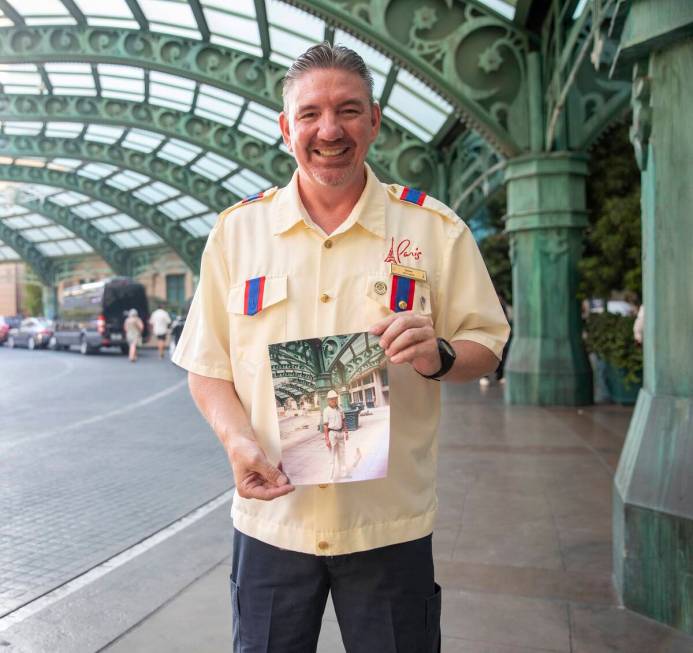 James Ealey, a Paris Las Vegas day-one employee, stands with a photograph from his first day of ...