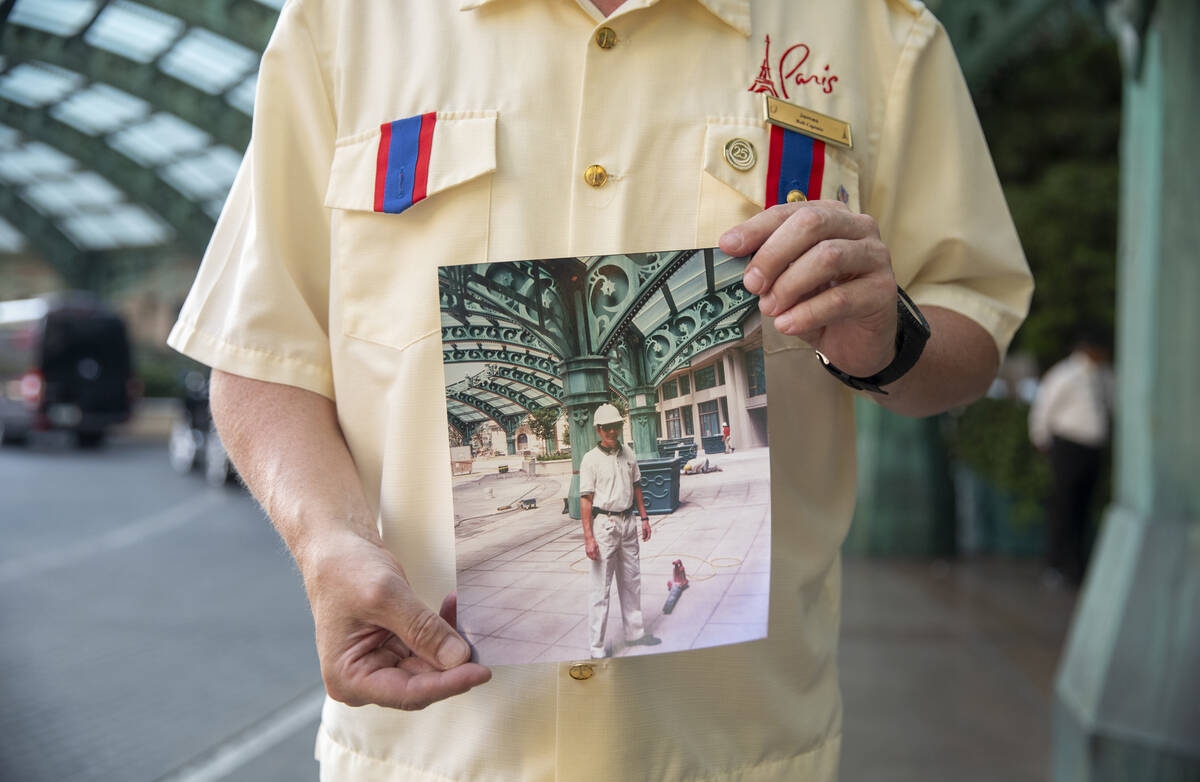 James Ealey, a Paris Las Vegas day-one employee, stands with a photograph from his first day of ...