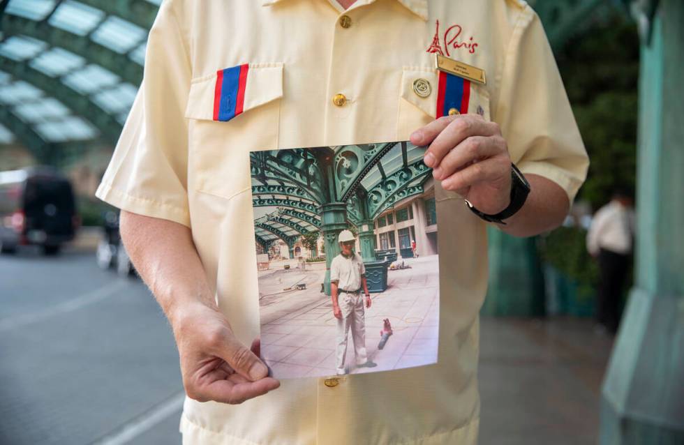 James Ealey, a Paris Las Vegas day-one employee, stands with a photograph from his first day of ...