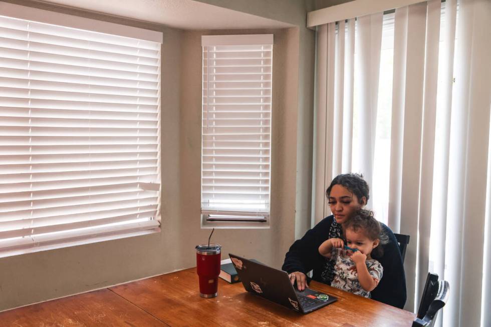 Katherine Sheffey works on her computer with her son Kyo Sheffey, 2, in her lap at one of the p ...