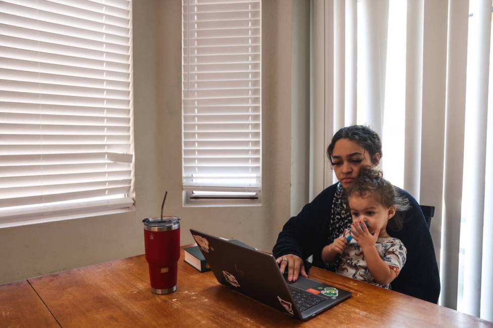 Katherine Sheffey works on her computer with her son Kyo Sheffey, 2, in her lap at one of the p ...