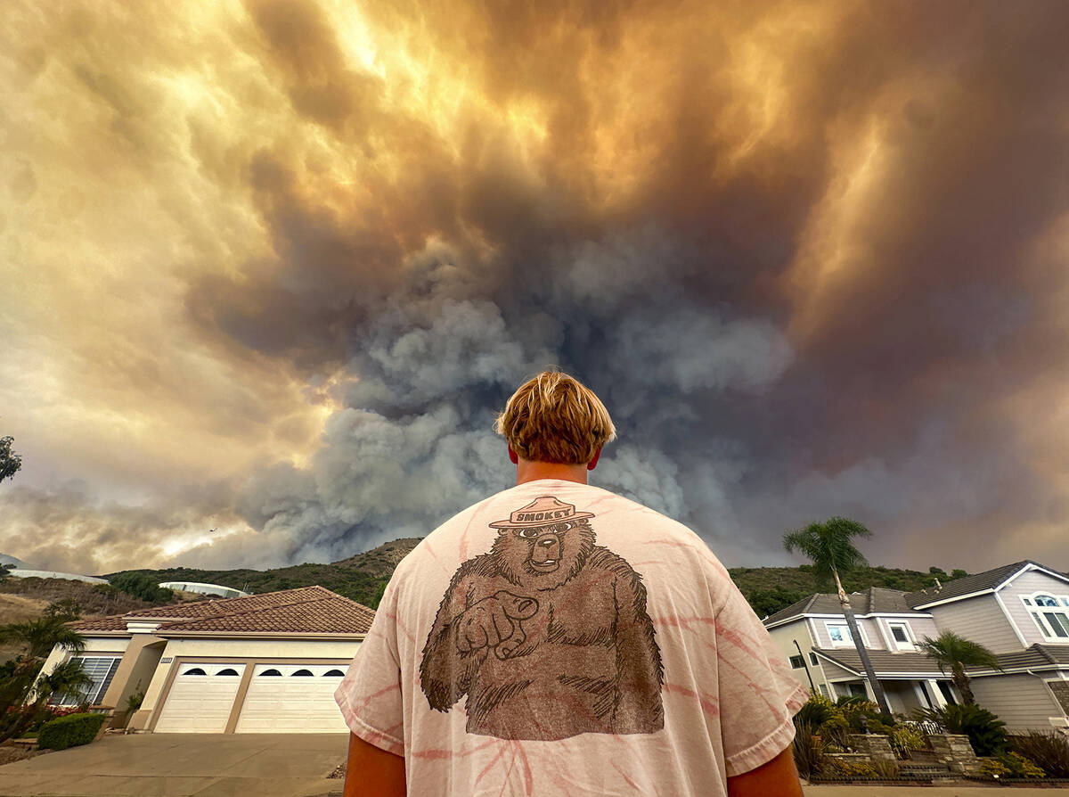 Aidan Thomas wears a Smokey Bear t-shirt as he watches smoke from the Airport Fire rise behind ...