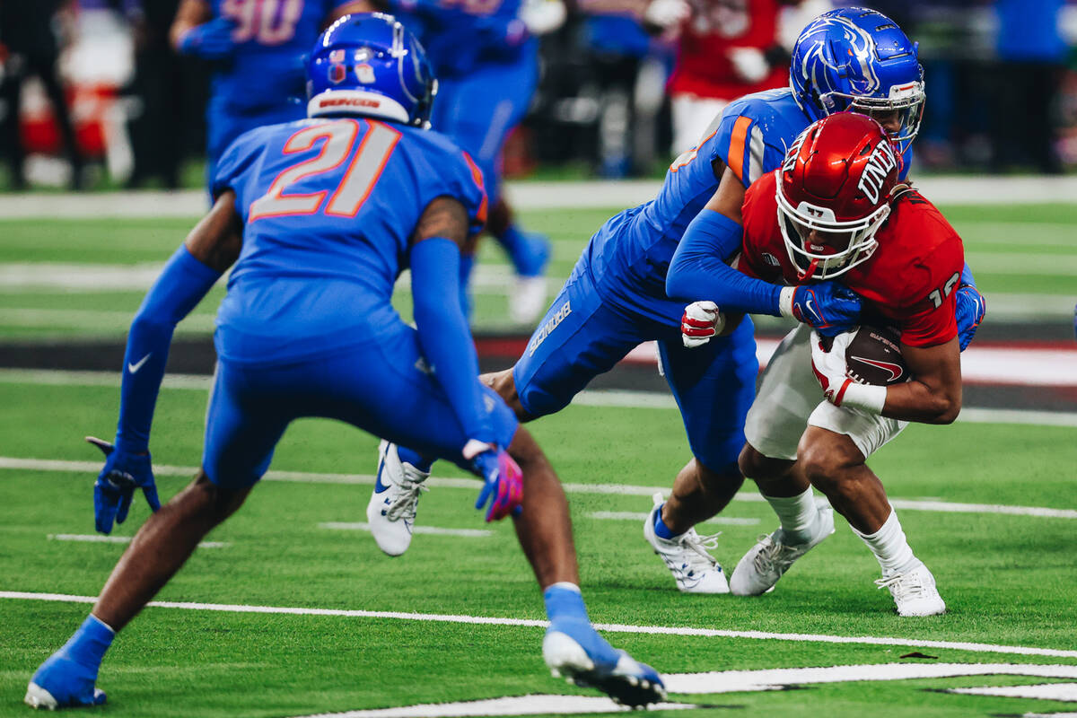 UNLV wide receiver DeAngelo Irvin Jr. (16) gets taken down by a Boise State defender during the ...