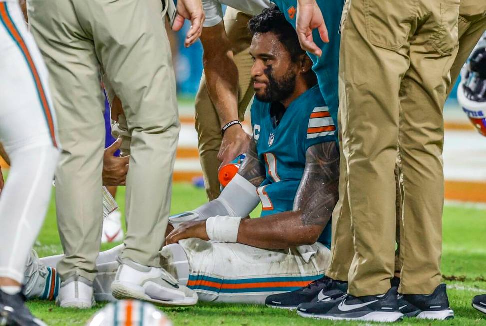 Miami Dolphins quarterback Tua Tagovailoa (1) sits on the field as he is attended to after an i ...