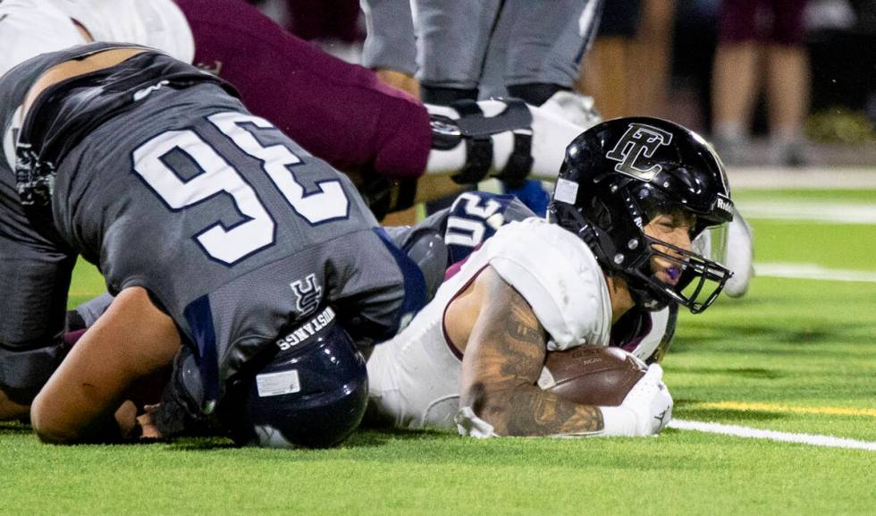 Faith Lutheran senior Cale Breslin (14) winces after being tackled during the high school footb ...