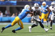 Los Angeles Chargers cornerback Kristian Fulton (7) pushes Raiders tight end Brock Bowers (89) ...