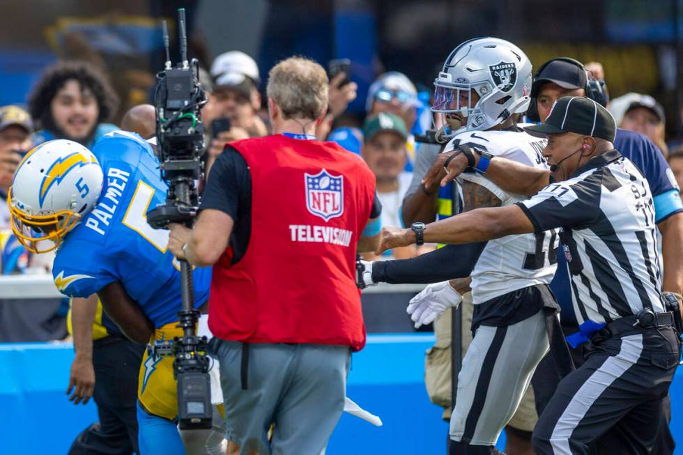 Raiders cornerback Jack Jones (18) is held back by officials on a fight with Los Angeles Charge ...