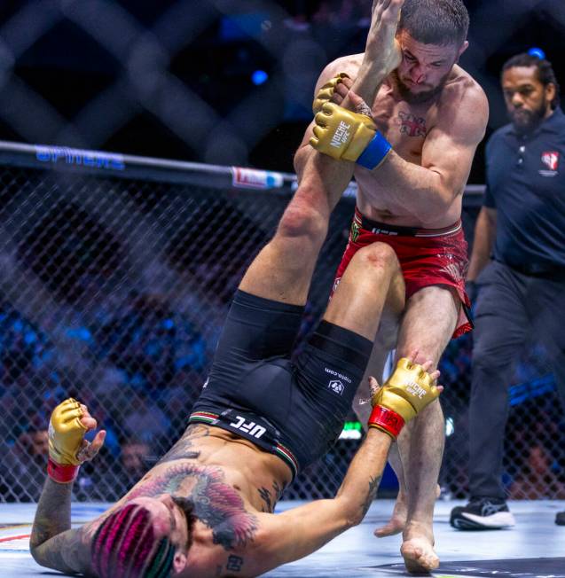 Sean O'Malley attempts to kick away Merab Dvalishvili above him in their bantamweight title fig ...