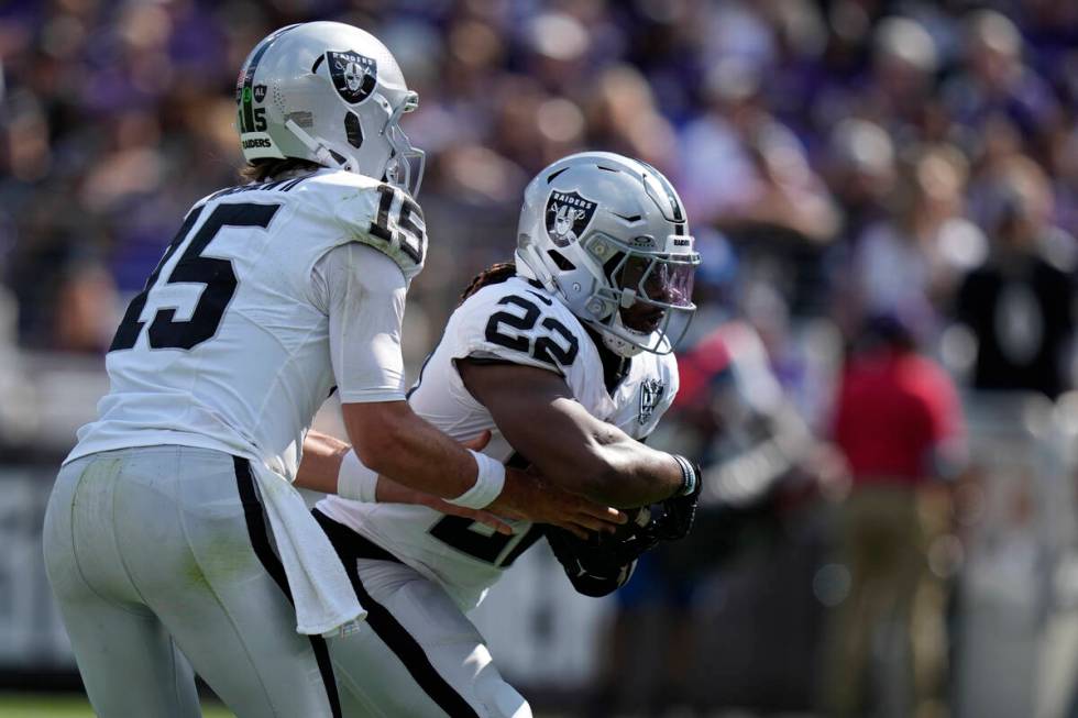 Las Vegas Raiders quarterback Gardner Minshew (15) hands the ball off to running back Alexander ...