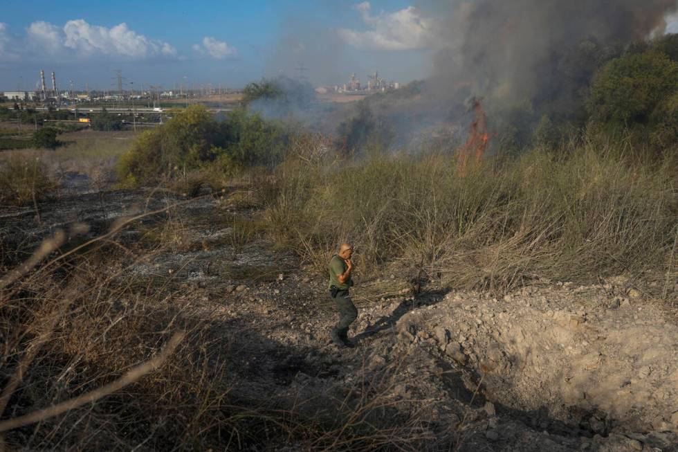 A police officer inspects the area around a fire after the military said it fired interceptors ...