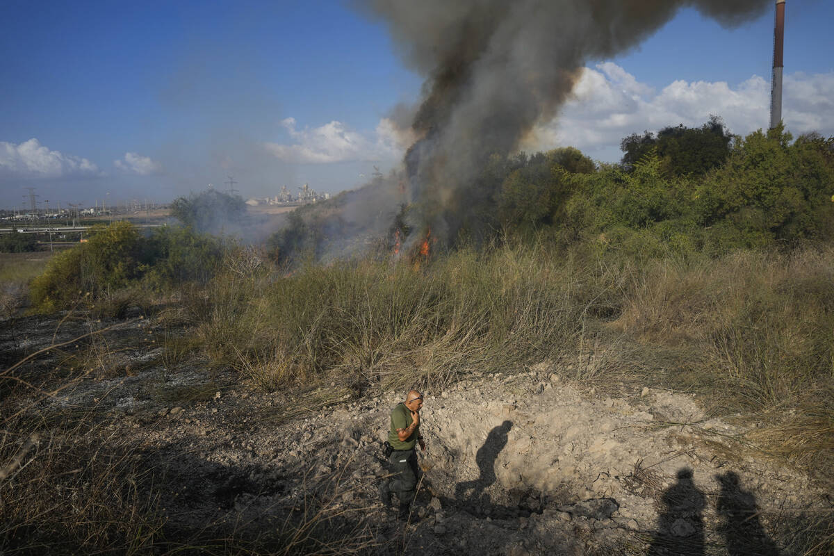 A police officer inspects the area around a fire after the military said it fired interceptors ...