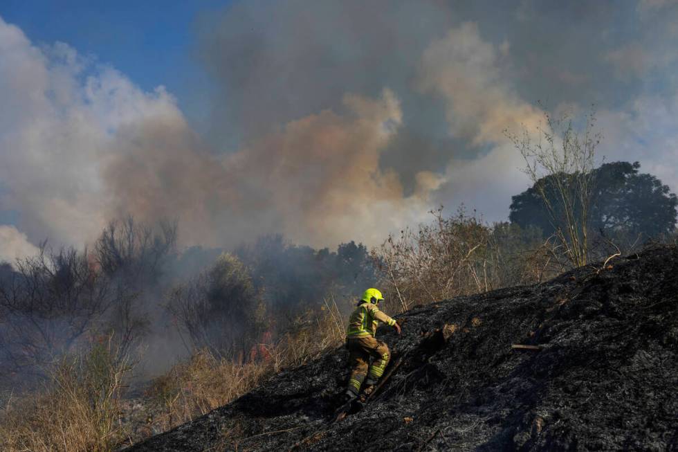 A firefighter works in the area around a fire after the military said it fired interceptors at ...