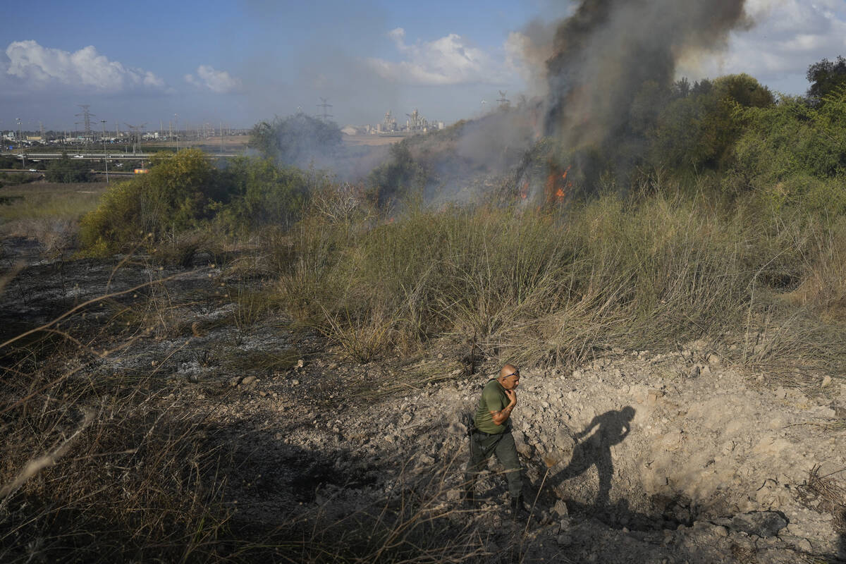 A police officer inspects the area around a fire after the military said it fired interceptors ...