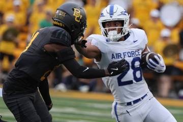 Air Force running back Aiden Calvert stiff-arms Baylor linebacker Keaton Thomas while running t ...