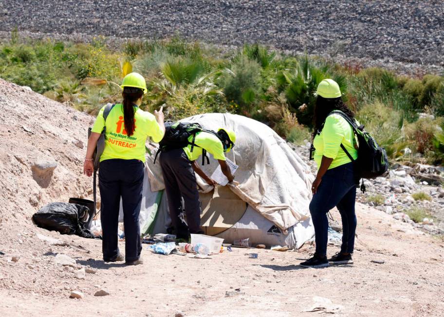 Rayvonte Toliver, center, places flyers on a homeless tent as Jaqueline Peeples, left, and Zabr ...