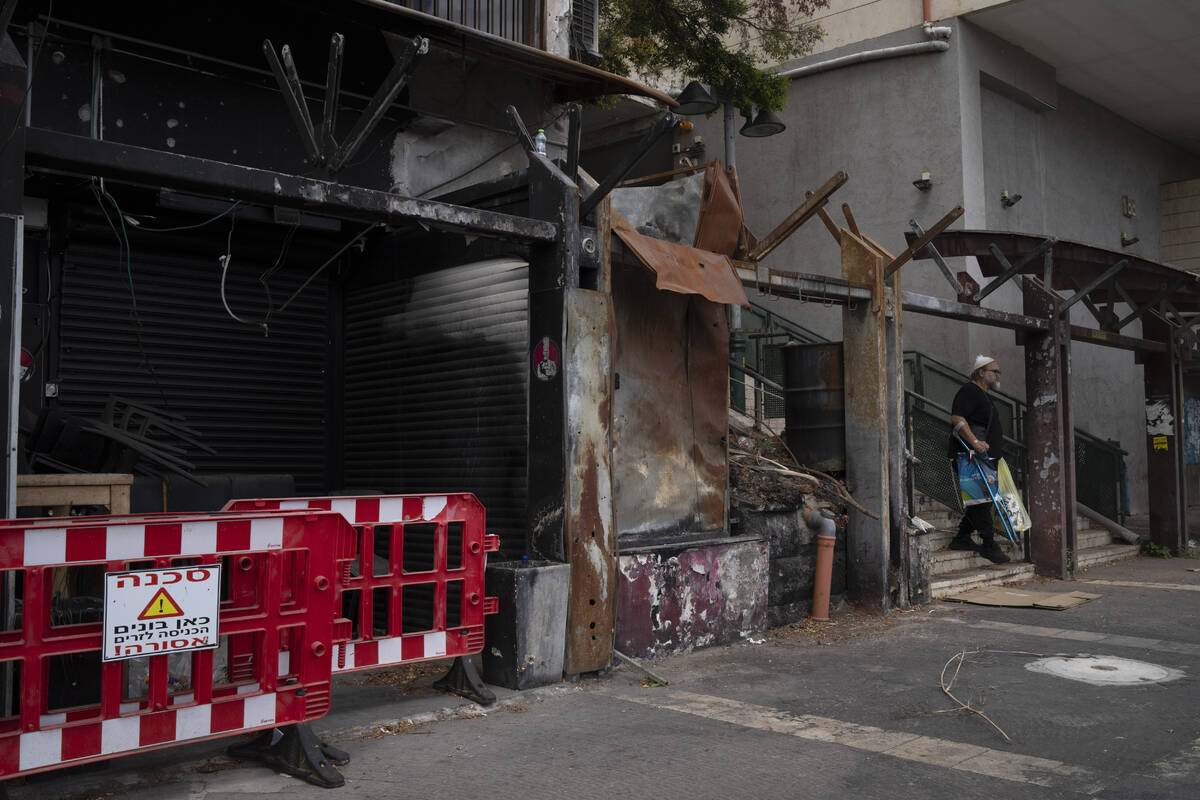 A man walks past a damaged shop, from previous shelling attacks from Lebanon, in Kiryat Shmona, ...