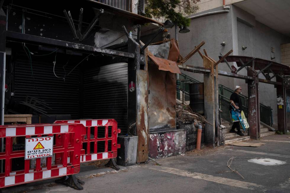 A man walks past a damaged shop, from previous shelling attacks from Lebanon, in Kiryat Shmona, ...