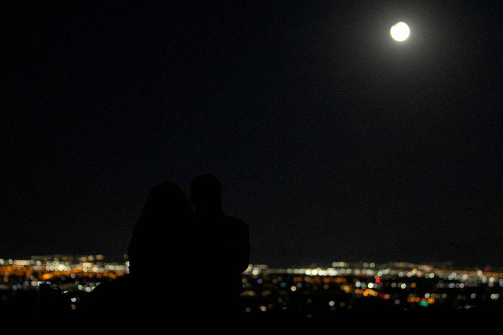 Ashley Prentiss, left, and Malik Anthony, right, watch the Harvest Moon Supermoon partial lunar ...