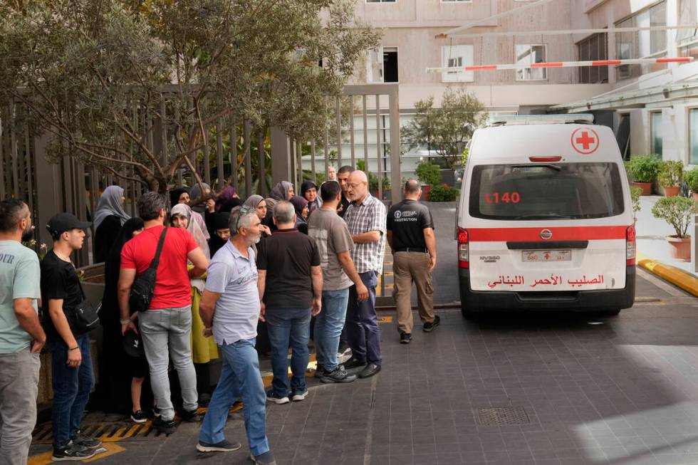 Lebanese Red Cross ambulance passes next of the families of victims who were injured on Monday ...