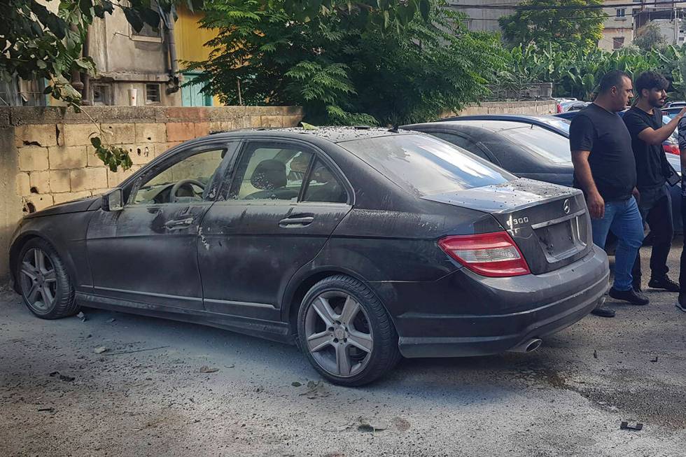 Lebanese security officers stand next of a partly damaged car after what is believed to be the ...