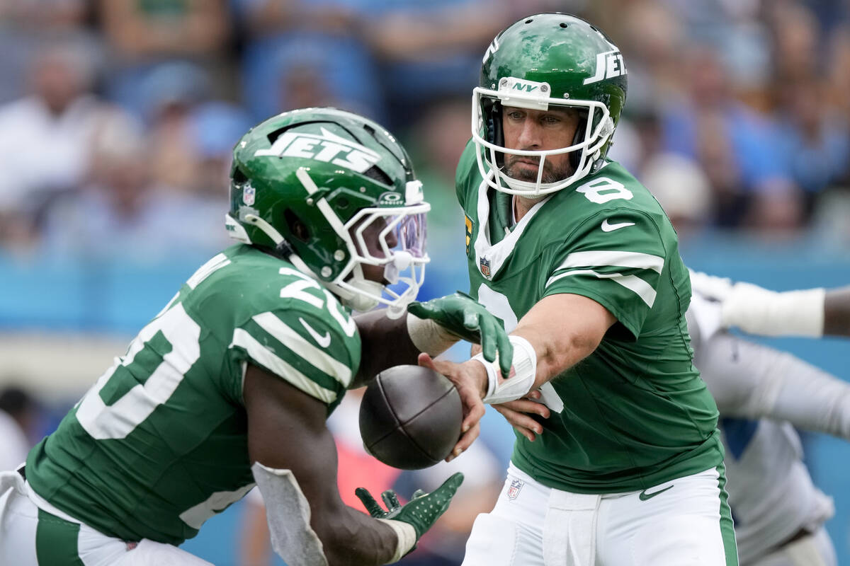 New York Jets quarterback Aaron Rodgers (8) hands the ball to running back Breece Hall (20) dur ...