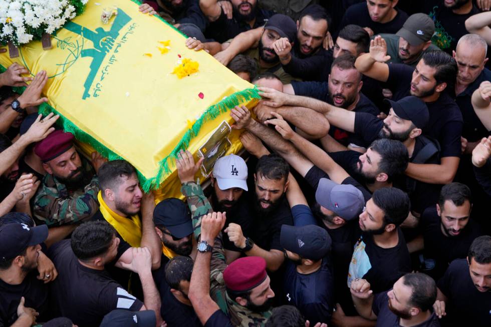 Hezbollah members carry the coffin of their comrade who was killed on Wednesday when a handheld ...