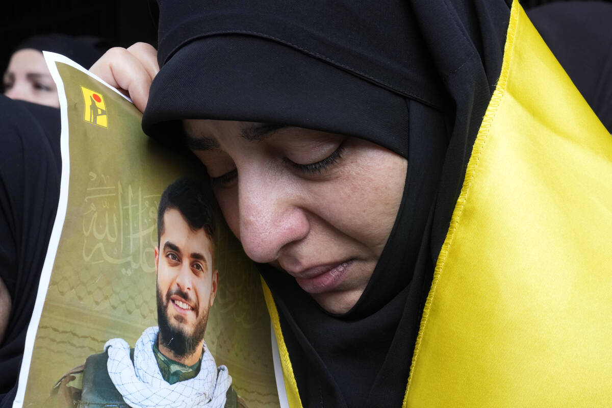 A woman holds a picture of a Hezbollah member who was killed on Wednesday when a handheld devic ...