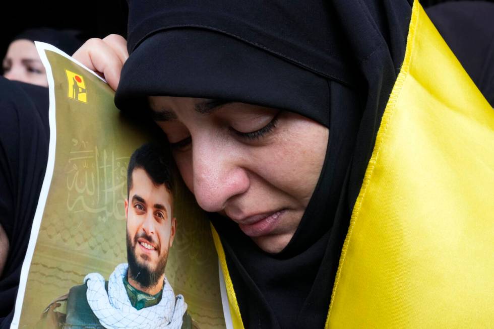 A woman holds a picture of a Hezbollah member who was killed on Wednesday when a handheld devic ...