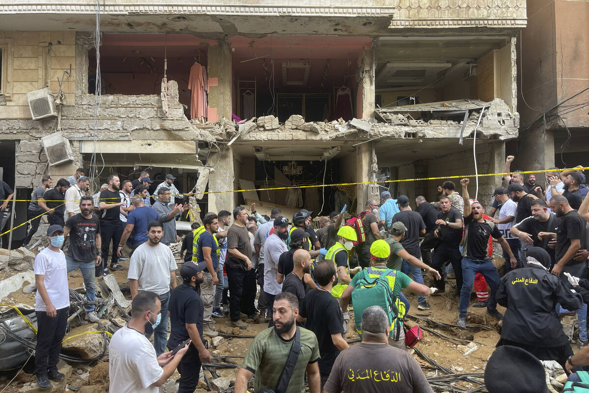 People gather near a damaged building at the scene of an Israeli missile strike in the southern ...