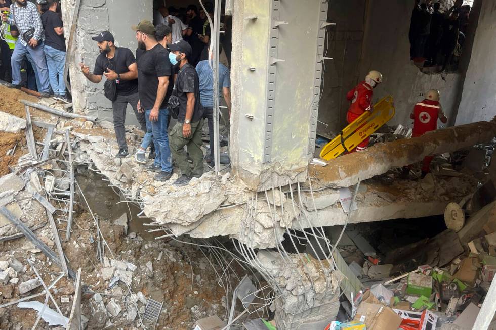 People and rescuers gather at the scene of an Israeli missile strike in the southern suburbs of ...