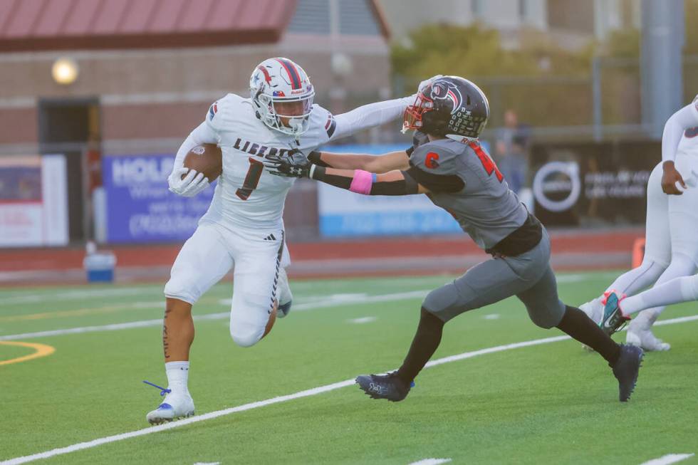 Liberty Running Back Ezra Sanelivi (1) stiff arms Coronado defender during a football game betw ...