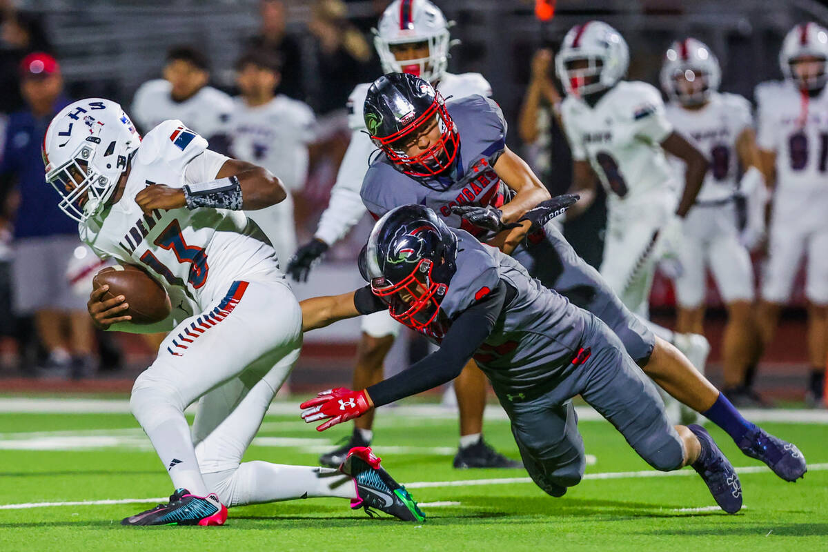 Liberty quarterback Jamar Malone (13) tries to escape the grasps of Coronado defenders during a ...