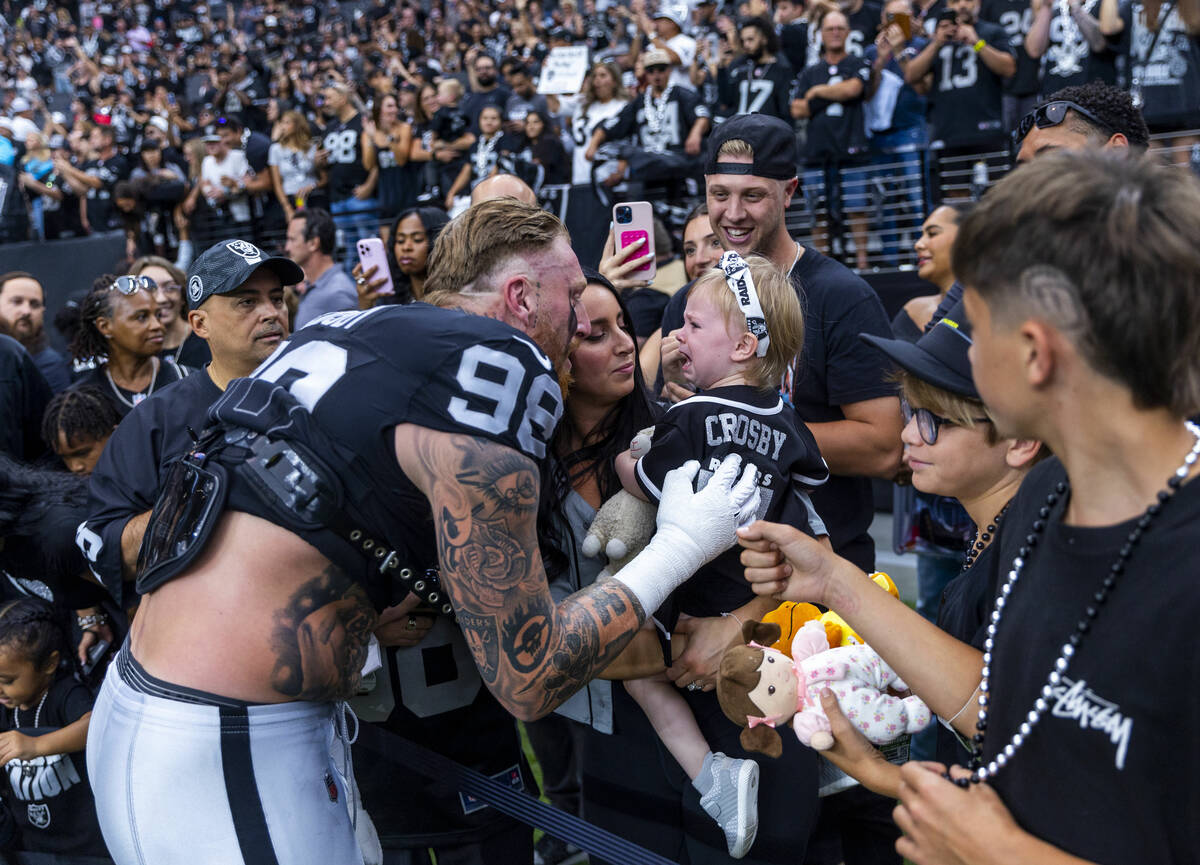 Raiders defensive end Maxx Crosby (98) attempts to get his daughter to stop crying as he greets ...