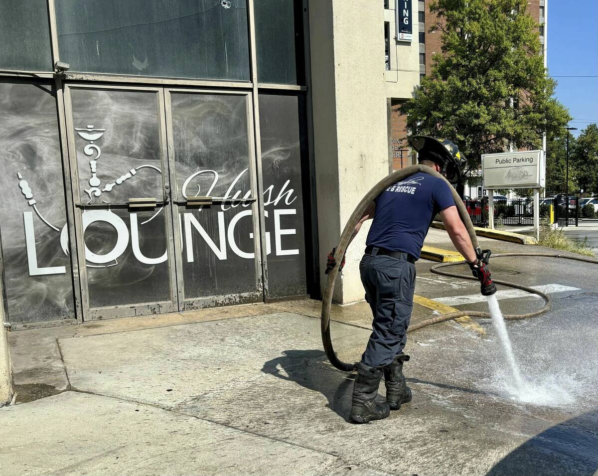 A firefighter cleans blood stains off the sidewalk outside a nightclub in Birmingham, Ala. on S ...